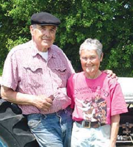 Two people smiling in front of the woods