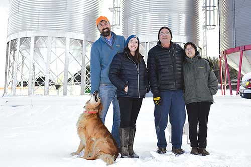 Two generations cultivate Aurora Mills & Farm. From the left and standing in front of some of the new silos: Marcus Flewelling, Sara Williams Flewelling, Matt and Linda Williams.