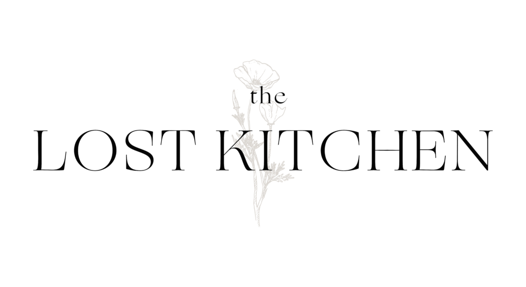 The Lost Kitchen logo: Text, the Lost Kitchen, in front of an illustration of a poppy stem with two flowers.