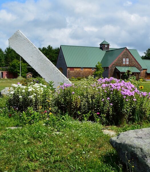 MOFGA's main building with a garden with a large slanted rock.