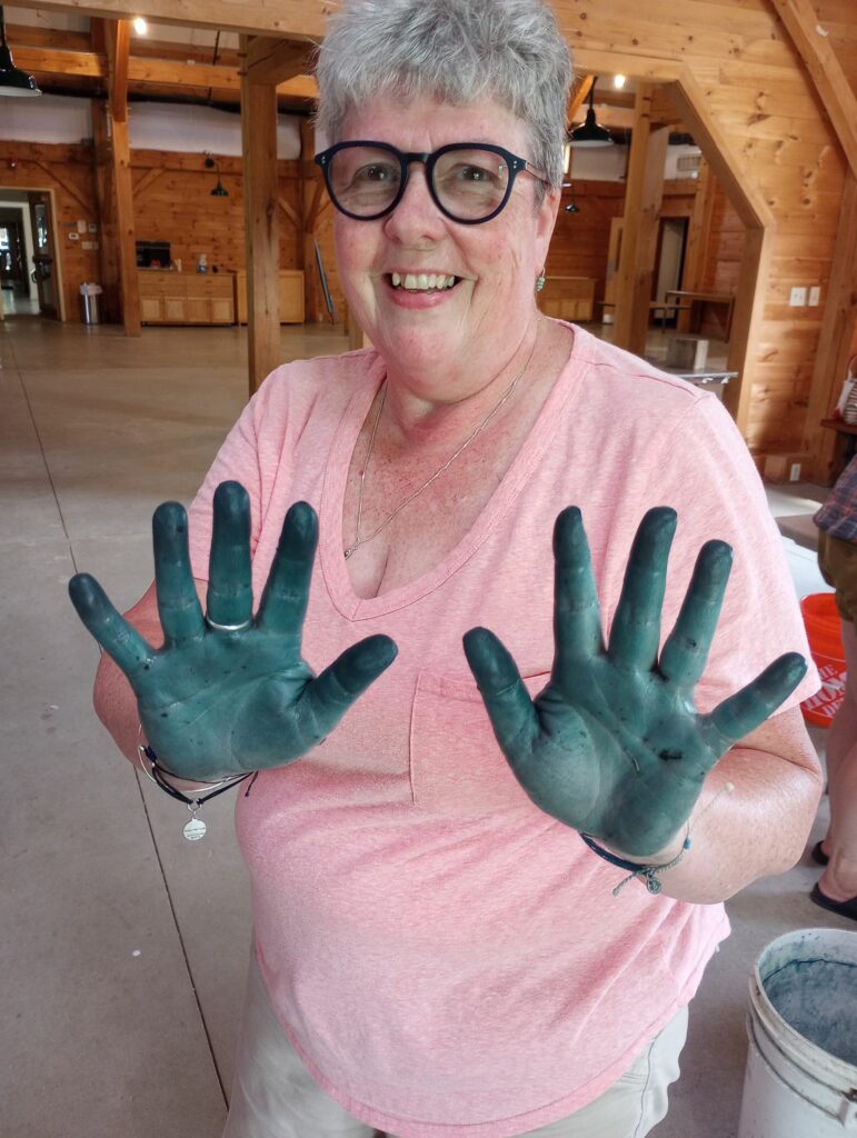 A class participant shows their blue dyed hands to the camera.