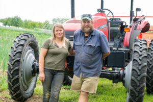 Two farmers stand in front of a large red tractor