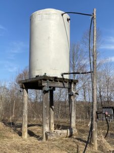 400-gallon tank up a on wooden platform for a gravity-fed water system