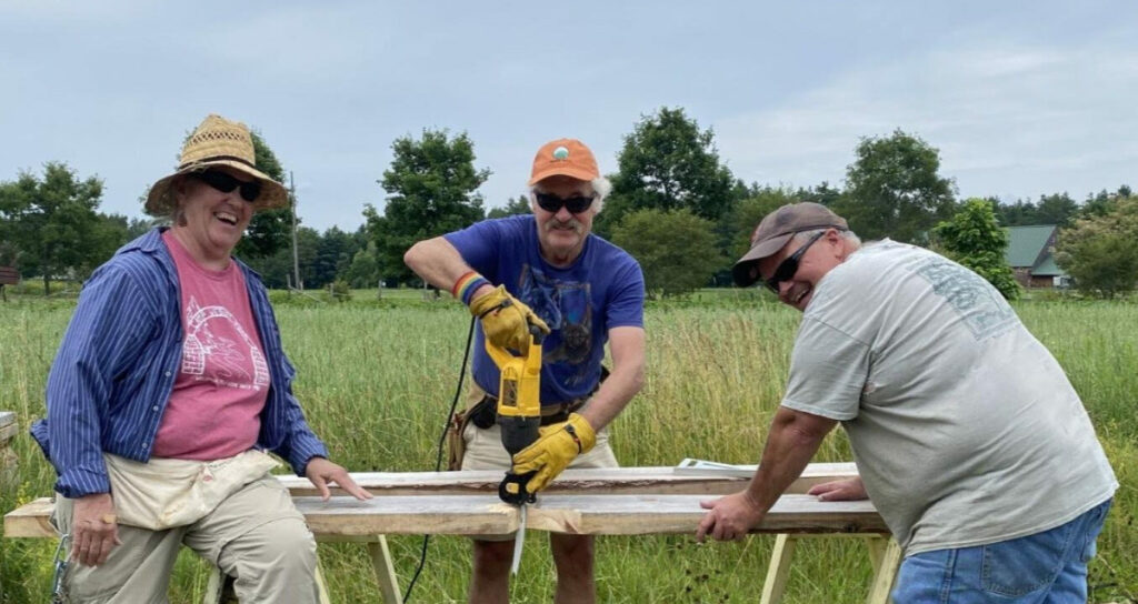 Three MOFGA volunteers wood work outside.