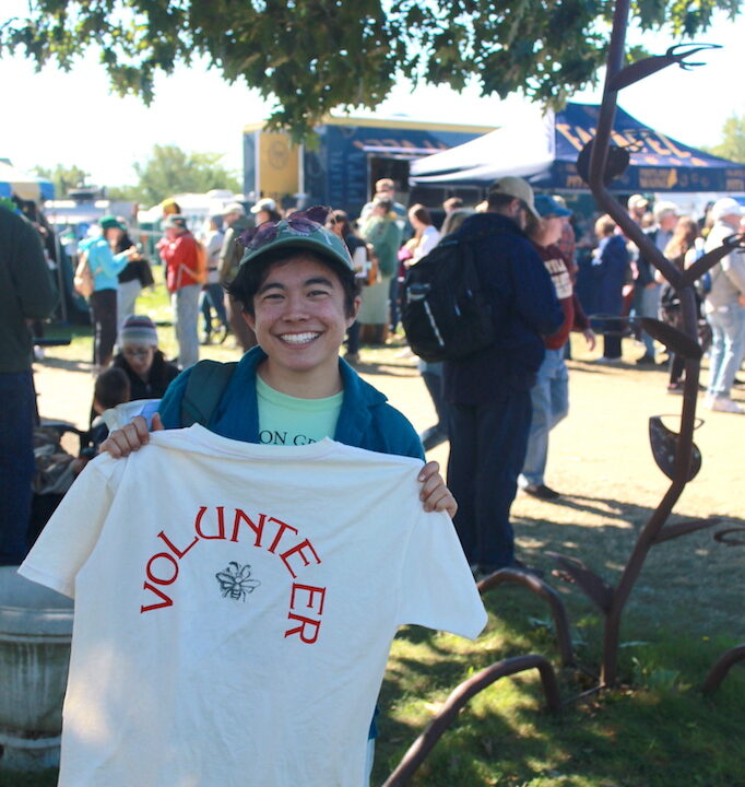 A Fair volunteer shows off their volunteer T-shirt.