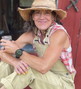 farmer smiling sitting in front of barn.