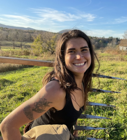 A farmer smiles holding a broadfork.