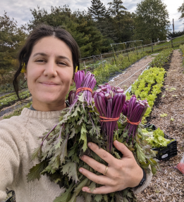 A farmer holding bundles of kale