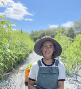 Farmer smiling sitting on black plastic in the field.