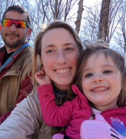 Two farmers smiling with child in woods