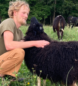 farmer kneeling with black sheep