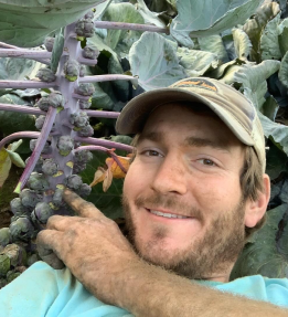 A farmer poses with Brussel sprouts