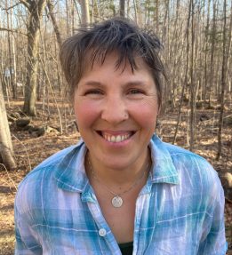 Volunteer Lisa Ravis smiles in the woods.